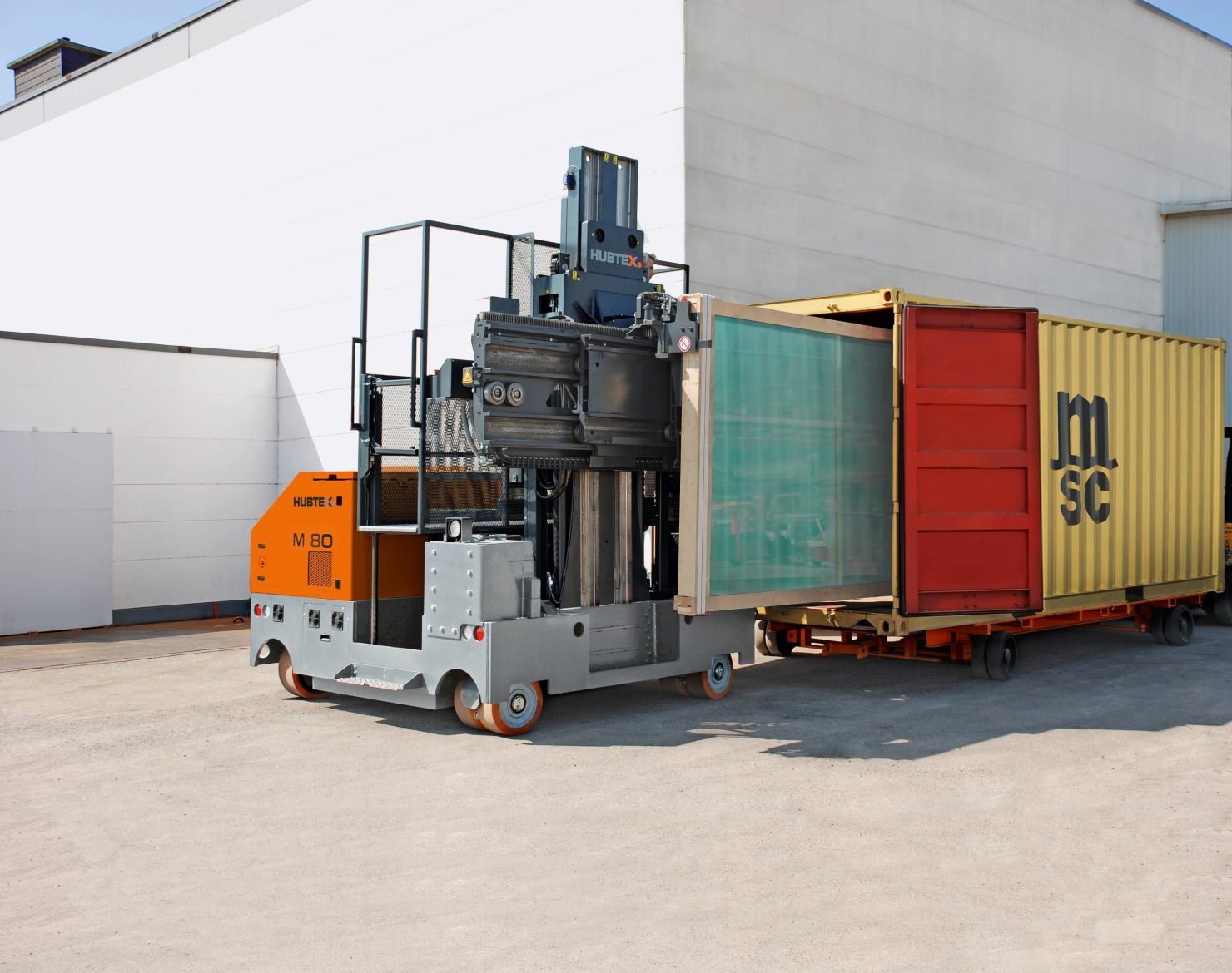 A HUBTEX M80 multidirectional sideloader loaded with a container