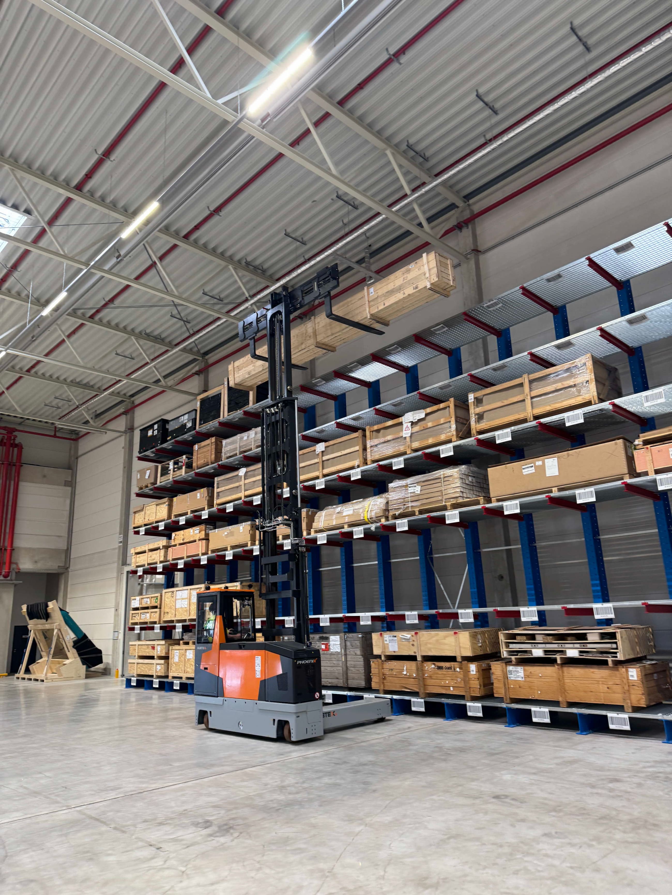 Phoenix Mehrwegestapler von Hubtex transportiert lange Holzpakete im Lager