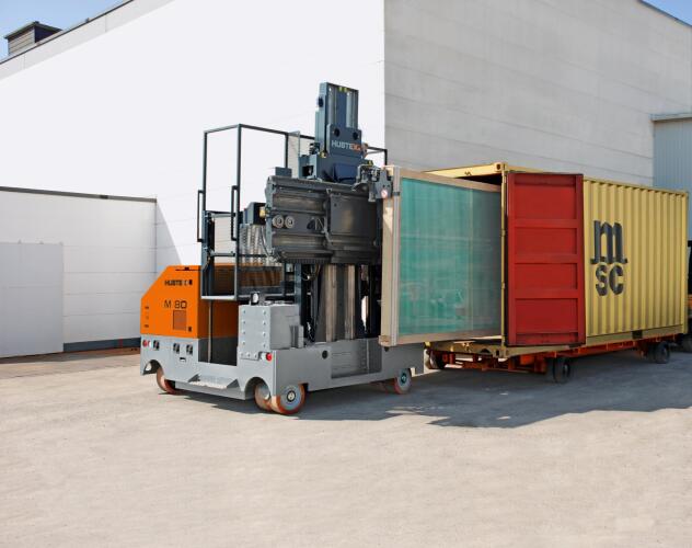 Ein HUBTEX M80 Mehrwege Seitenstapler beim Beladen eines Containers