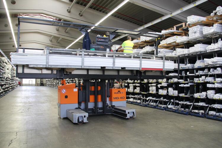 Der HUBTEX MQ 40 Seitenstapler beim Handeln von Kunststoffprofilen