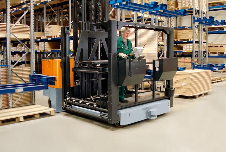 A selecionadora de pedidos elétrica multidirecional para operação bilateral MK da HUBTEX entrando em um corredor de estantes