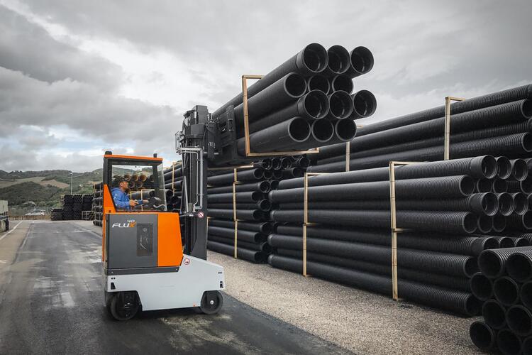 FluX counterbalanced compact forklift transports pipes in outdoor storage