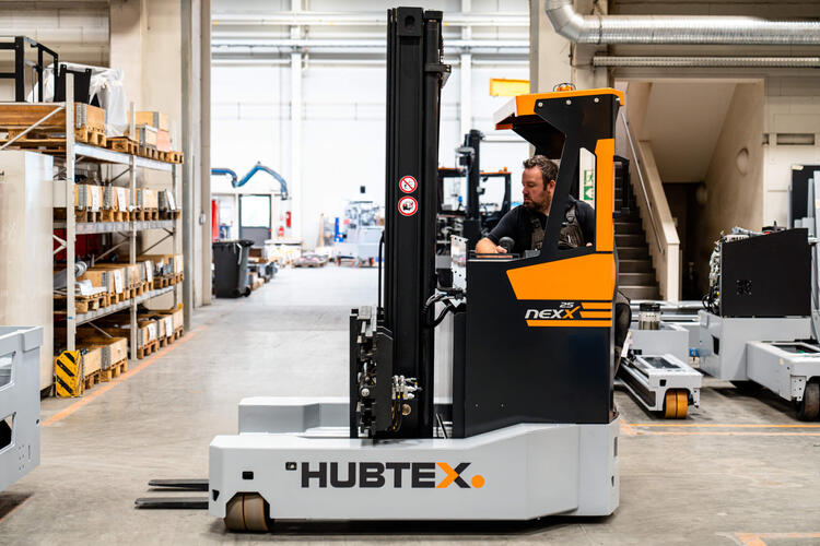Nexx Mehrwege Schubmaststapler fährt quer im Gang