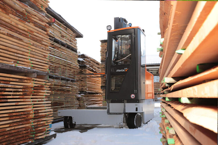 Mehrwegestapler transportiert Holz im Sägewerk im Schnee