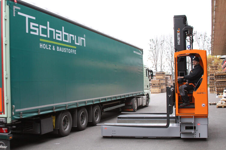 Hubtex Mehrwegestapler steht neben LKW