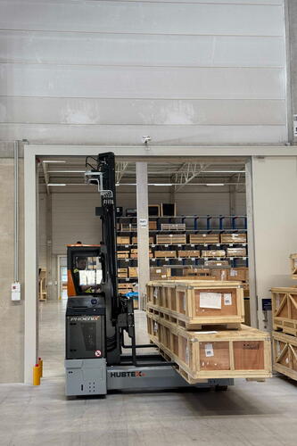 Mehrwegestapler Phoenix transportiert langes Holzmaterial durch ein Tor