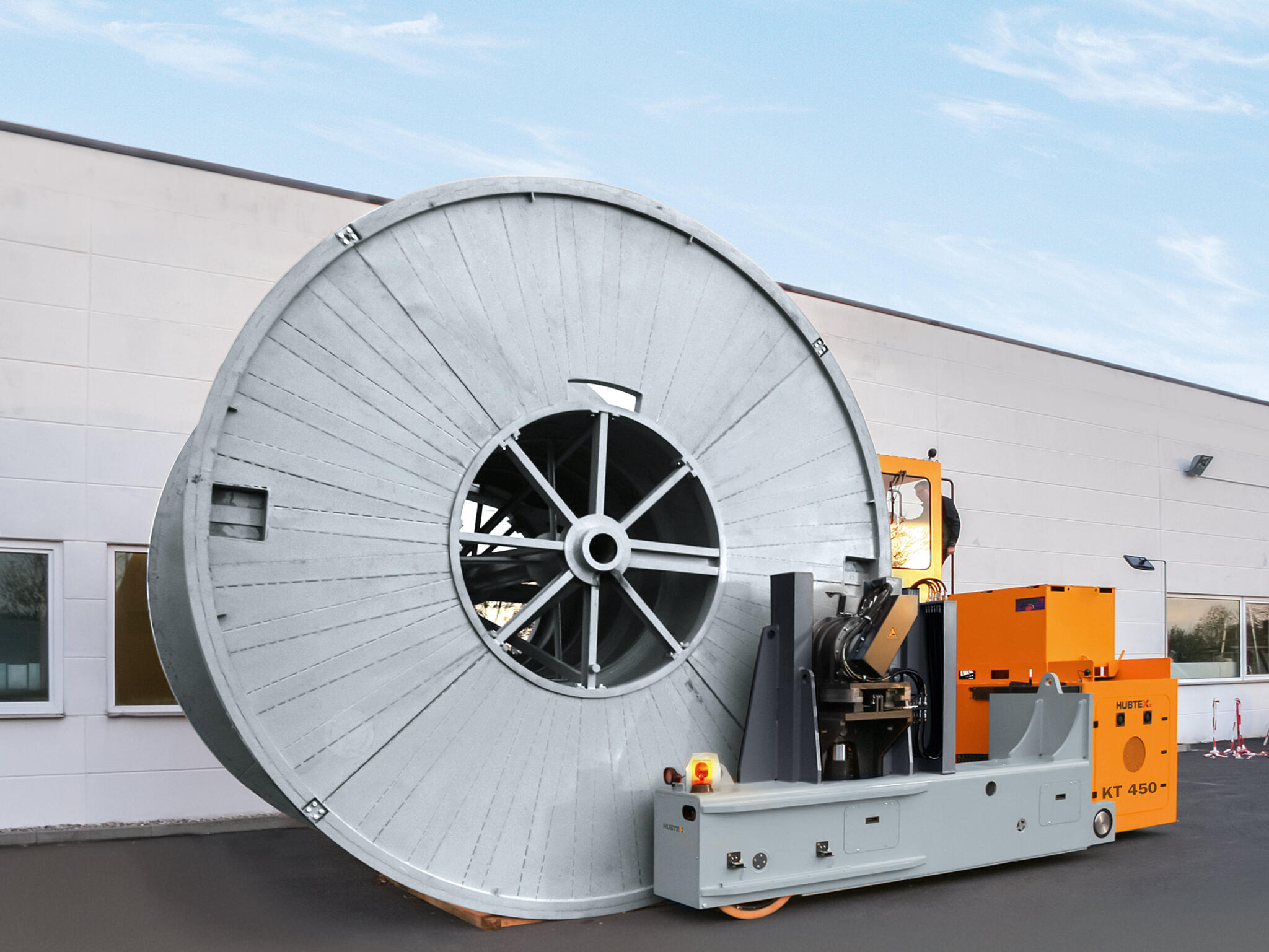 A drum transporter straddling a cable drum.