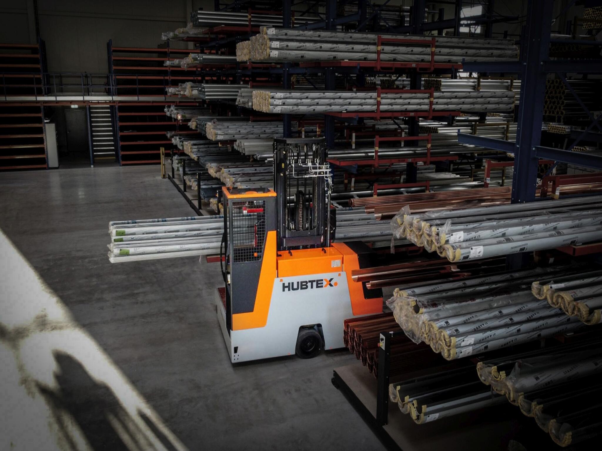 Basix Mehrwegestapler Hubtex transportiert Rohre in engen Gängen