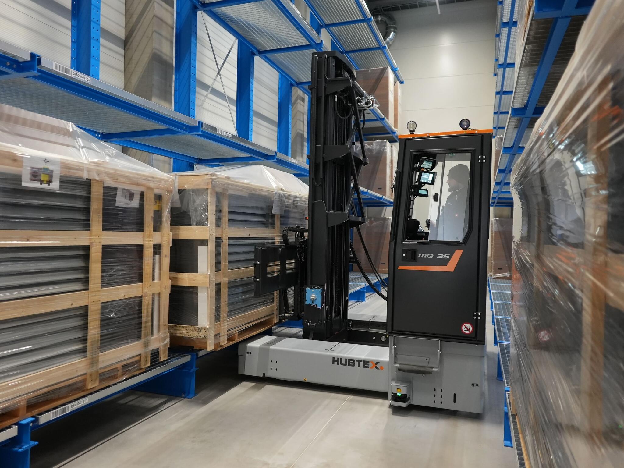 Hubtex Mehrwege- Seitenstapler Phoenix  lagert Ware im Schmalgang aus