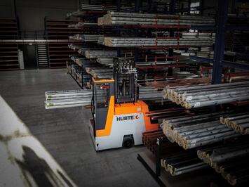 Basix Mehrwegestapler Hubtex transportiert Rohre in engen Gängen