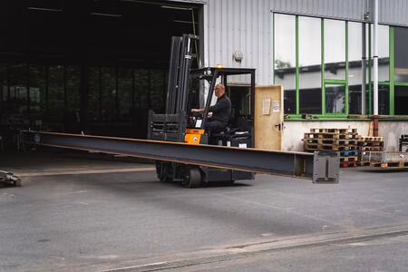 Mehrwegestapler Flux transportiert langes Rohr durch Hallentor