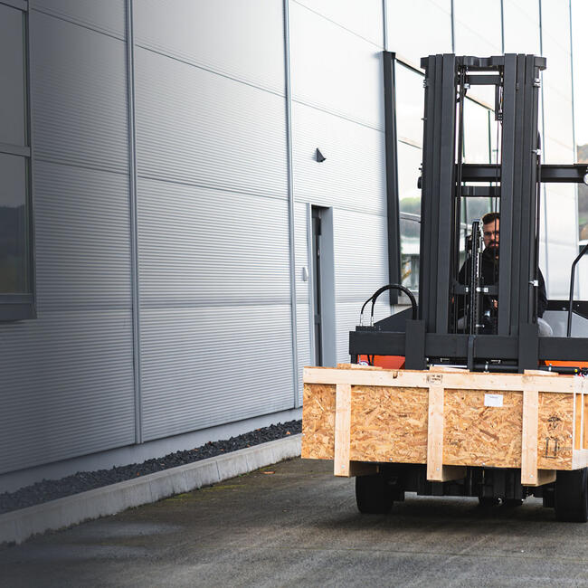 FLUX Stapler transportiert eine Holzkiste als Frontstapler