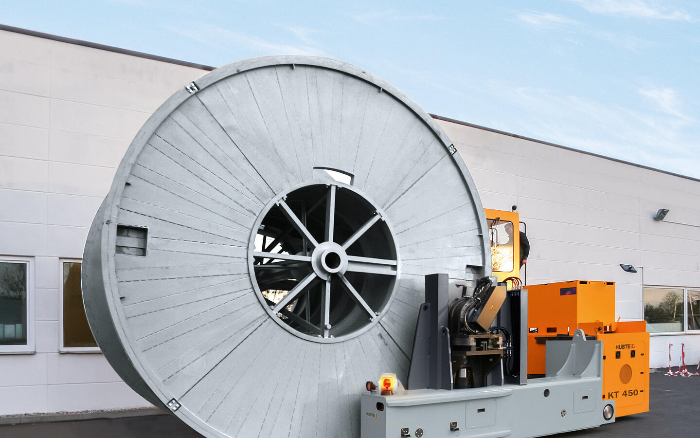 A drum transporter straddling a cable drum.