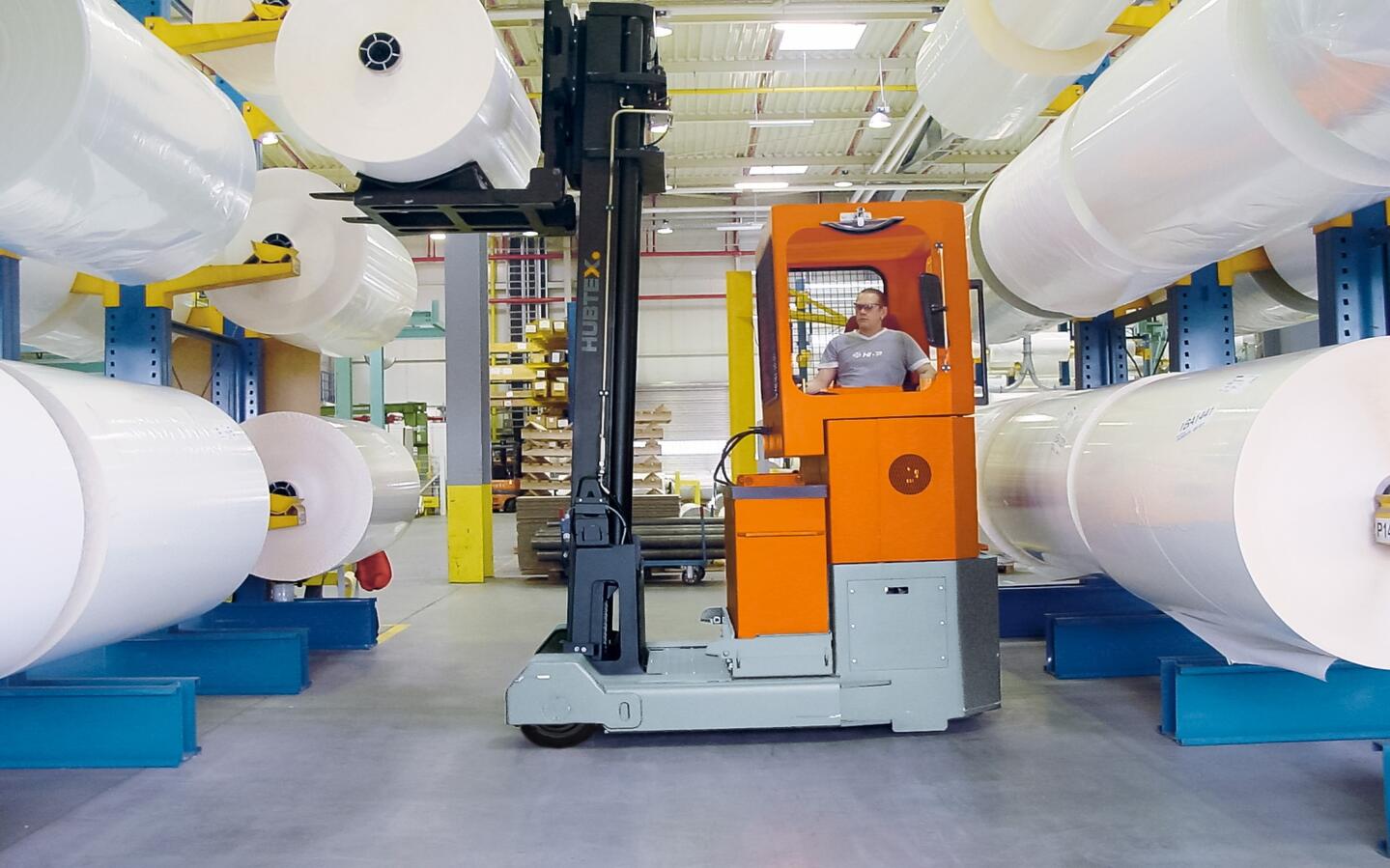 Una carretilla retráctil manipula rollos de papel.
