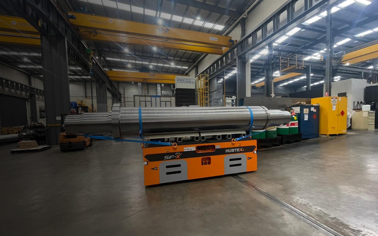 Kompakte SFX 20 Schwerlastplattform transportiert lange zylindrische Komponenten in einer Industriehalle